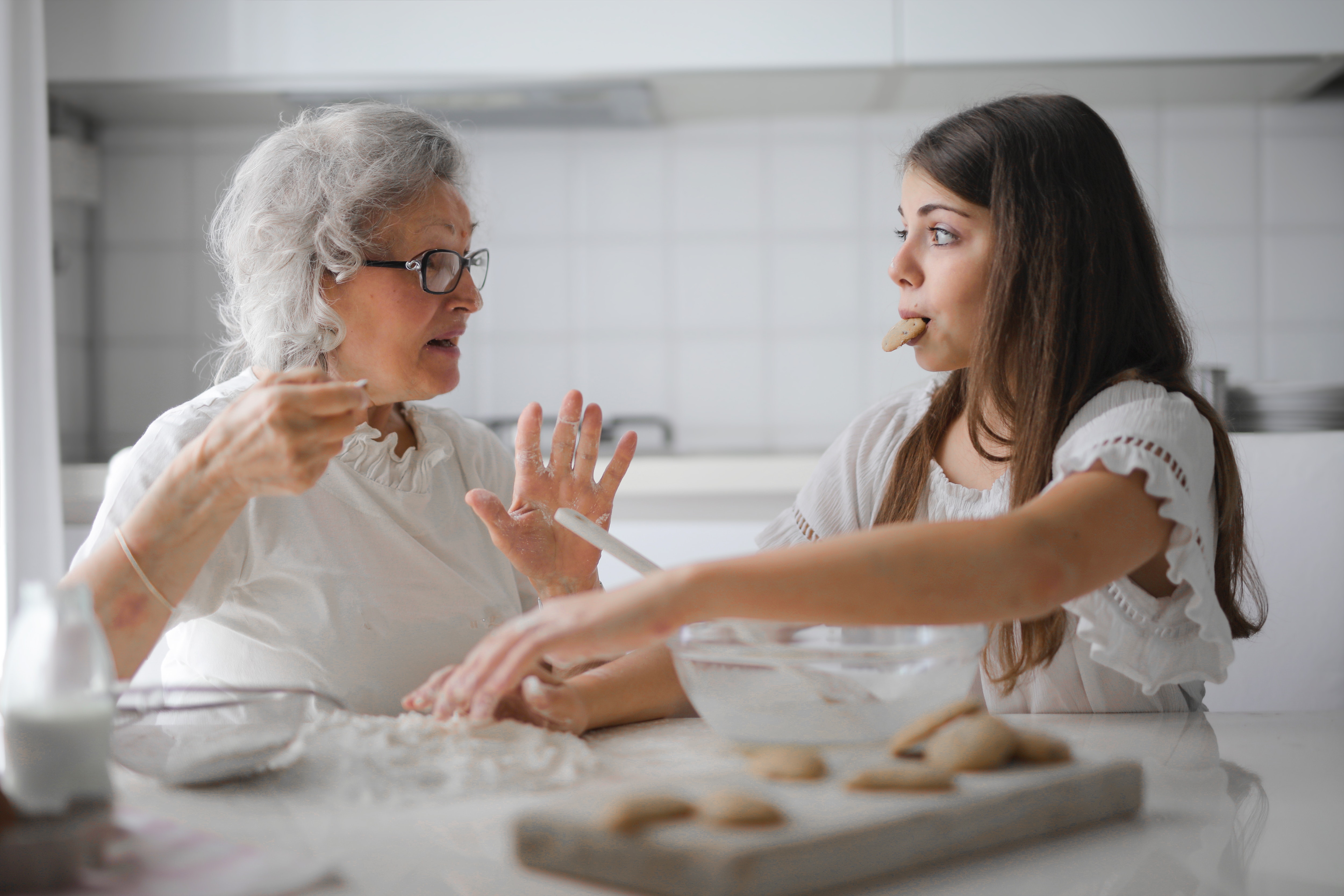 grand-mère et jeune fille discutant assises en faisant de la cuisine