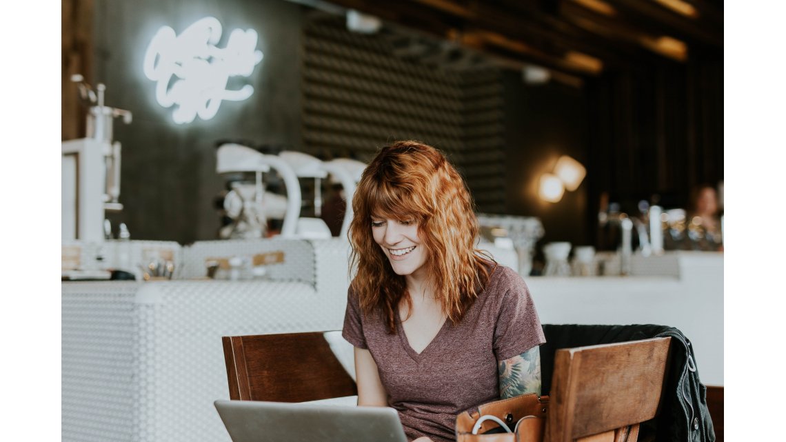 jeune femme souriante consultant un ordinateur dans un café